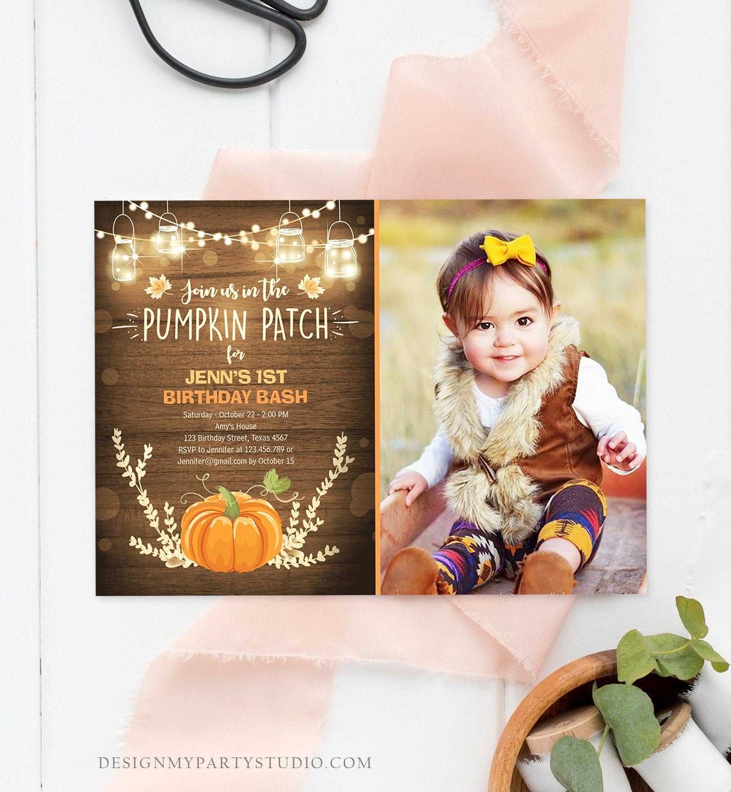 May include: A rustic brown wood background with a pumpkin patch theme birthday invitation. The invitation has a photo of a baby girl wearing a brown vest and a yellow bow. The text on the invitation reads &#39;Join us in the Pumpkin Patch for Jenn&#39;s 1st Birthday Bash&#39;.