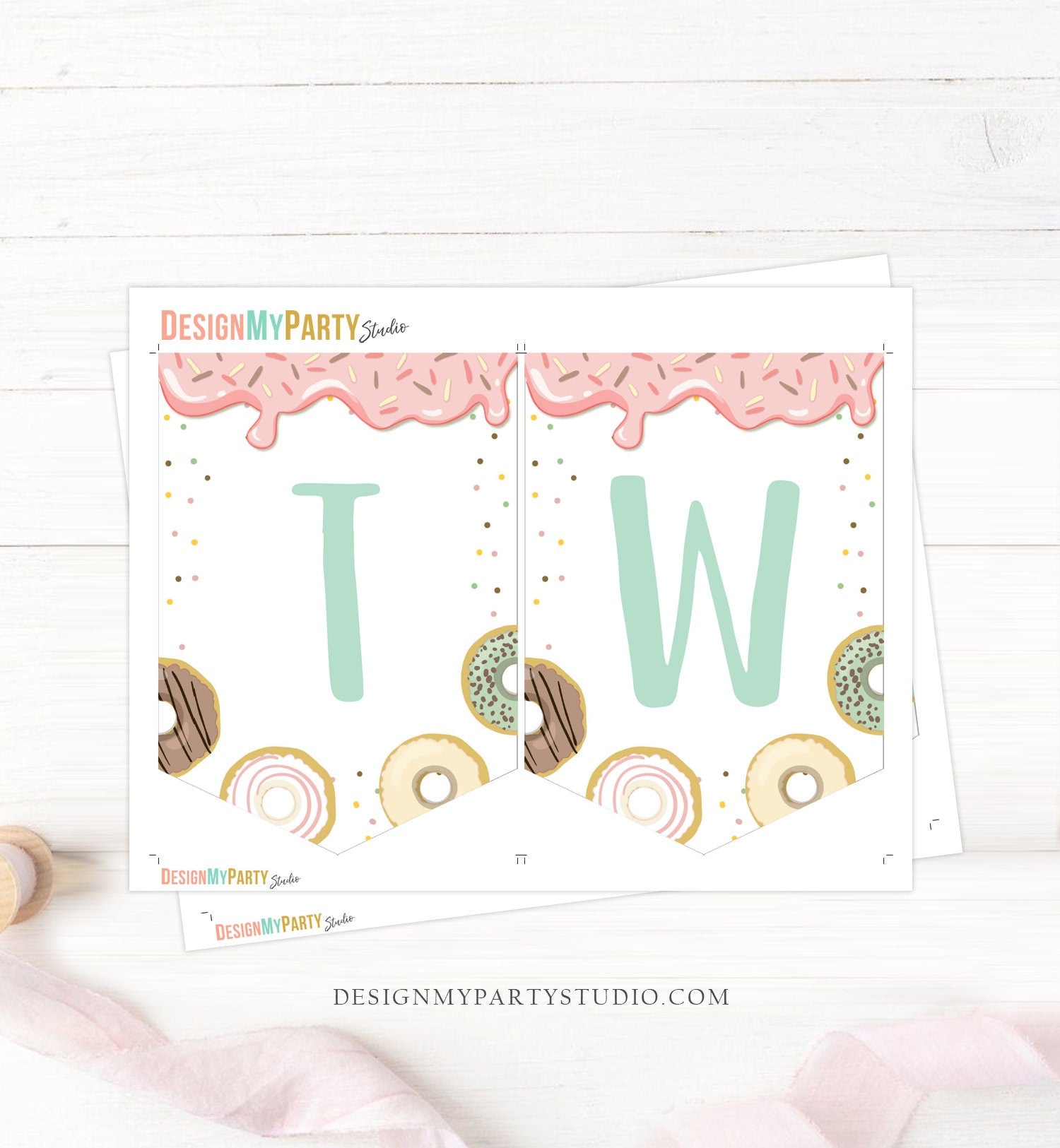 May include: A high chair with a pink and white donut themed banner that says &#39;TWO&#39; with sprinkles and a donut graphic. The banner has a scalloped edge and is decorated with pink and white ribbon and a white tassel garland.