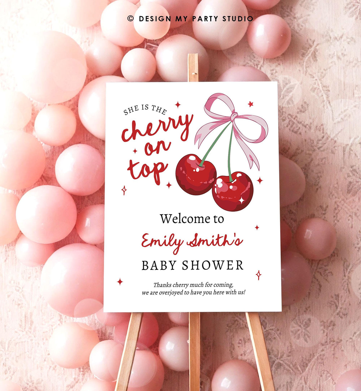 May include: A white sign with red and pink text and illustrations. The text reads &amp;#39;She is the cherry on top. Welcome to Emily Smith&amp;#39;s Baby Shower. Thanks cherry much for coming, we are overjoyed to have you here with us!&amp;#39; The sign has a red cherry with a pink ribbon on top of it.