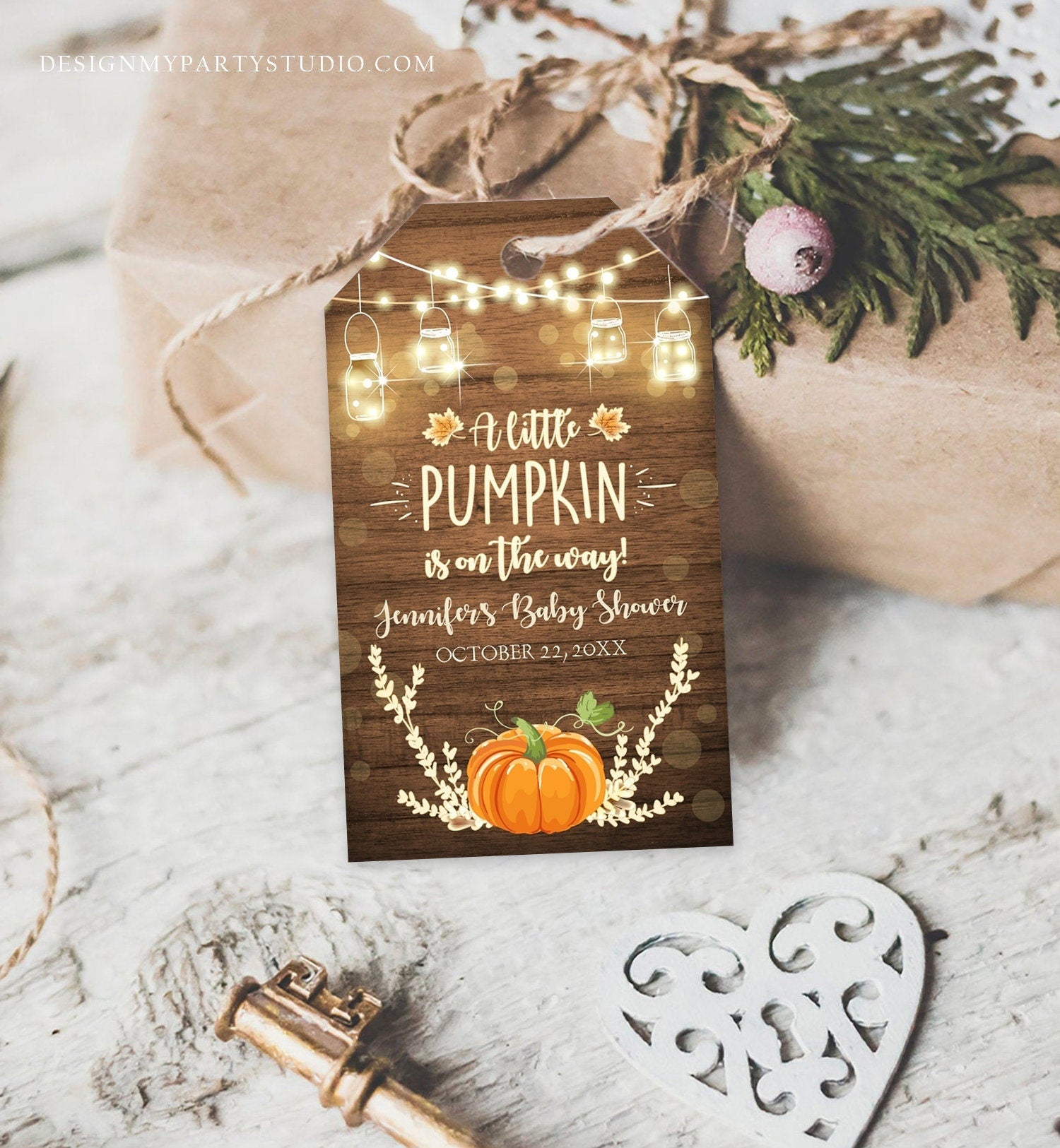 May include: A rustic brown wood baby shower favor tag with a pumpkin, lights, and leaves. The text on the tag reads 'A little pumpkin is on the way! Jennifer's Baby Shower October 22, 20XX'