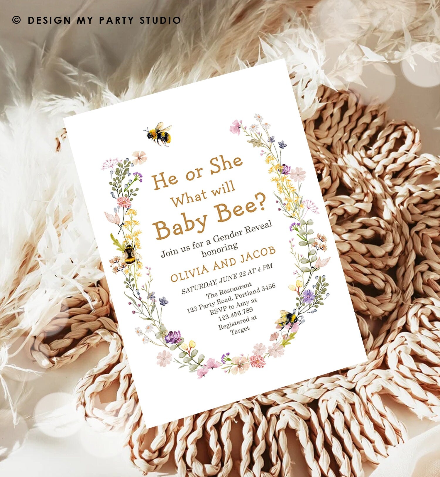 May include: A gender reveal party invitation with a floral wreath border. The invitation is white with gold text. The text reads: &#39;He or She What will Baby Bee?&#39;  Join us for a Gender Reveal honoring Olivia and Jacob. Saturday, June 22 at 4 PM. The Restaurant 123 Party Road, Portland 3456. RSVP to Amy at 123.456.789. Registered at Target.