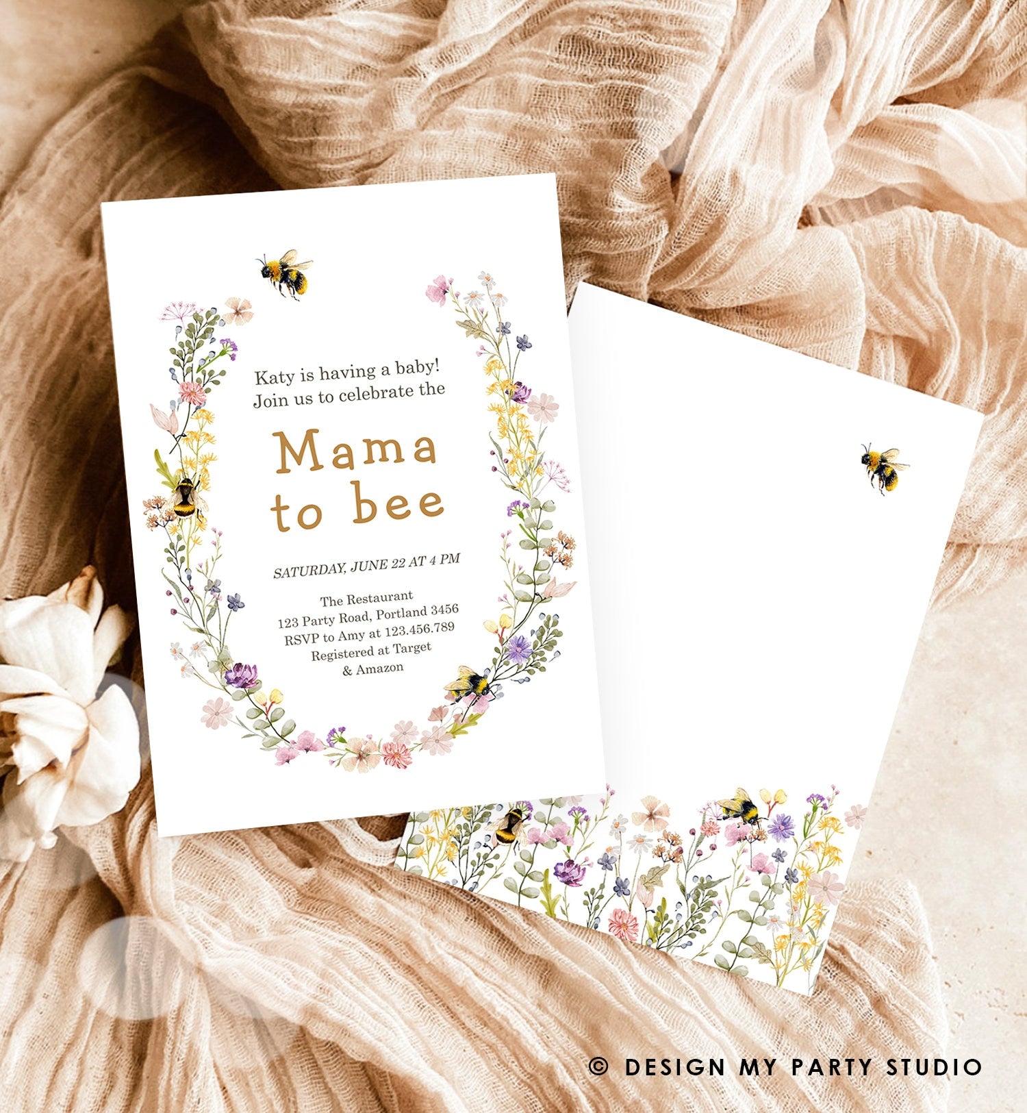 May include: A white baby shower invitation with a floral wreath border. The wreath is made of yellow, pink, and purple flowers and green leaves. There are bees on the wreath. The text on the invitation reads &#39;Katy is having a baby! Join us to celebrate the Mama to bee. Saturday, June 22 at 4 PM. The Restaurant 123 Party Road, Portland 3456. RSVP to Amy at 123.456.780. Registered at Target & Amazon.&#39;