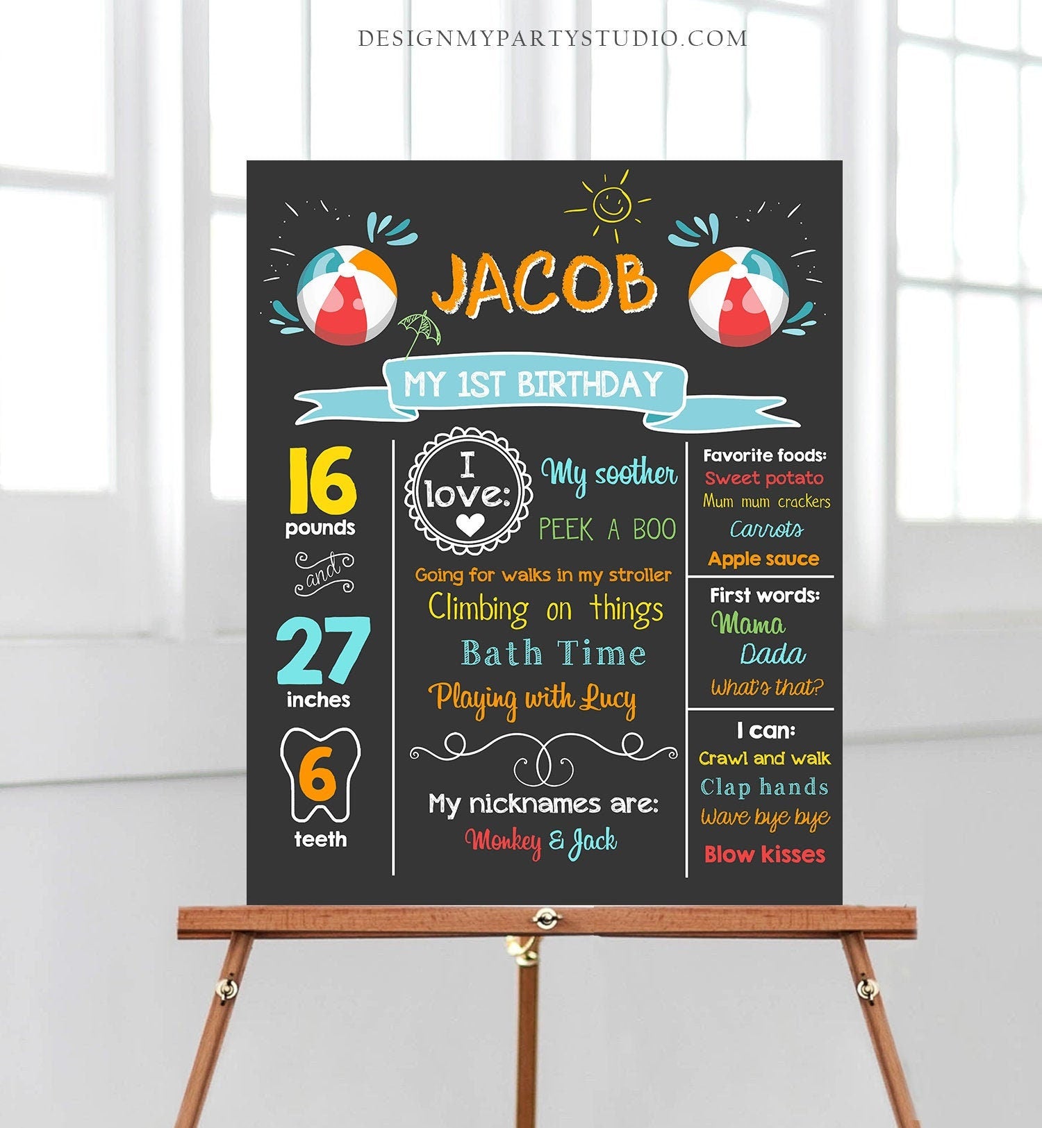 May include: A chalkboard style birthday sign with the name Jacob and the text &#39;My 1st Birthday&#39;. The sign is decorated with beach ball graphics and includes details about Jacob&#39;s age, weight, height, favorite things, and milestones. The sign is on a wooden easel.