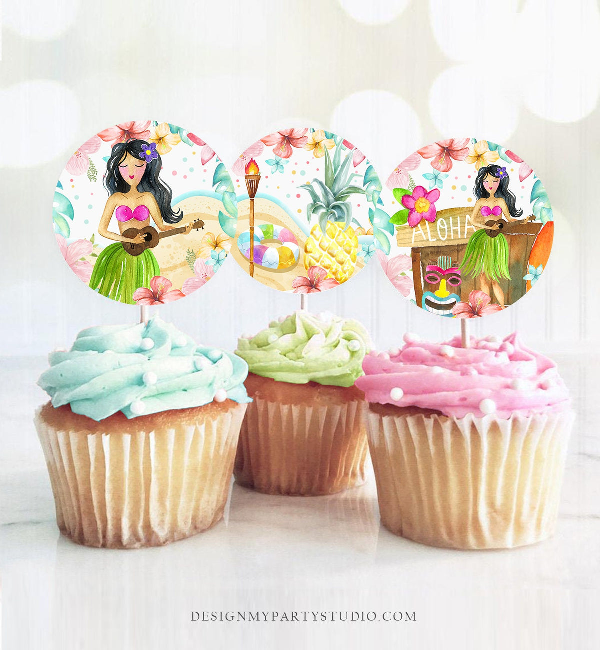 May include: Three cupcake toppers with a tropical theme. The toppers are round and feature a watercolor illustration of a woman in a hula skirt playing a ukulele, a pineapple, and a tiki hut with the word &amp;#39;Aloha&amp;#39; on it. The toppers are on top of cupcakes with different colored frosting.