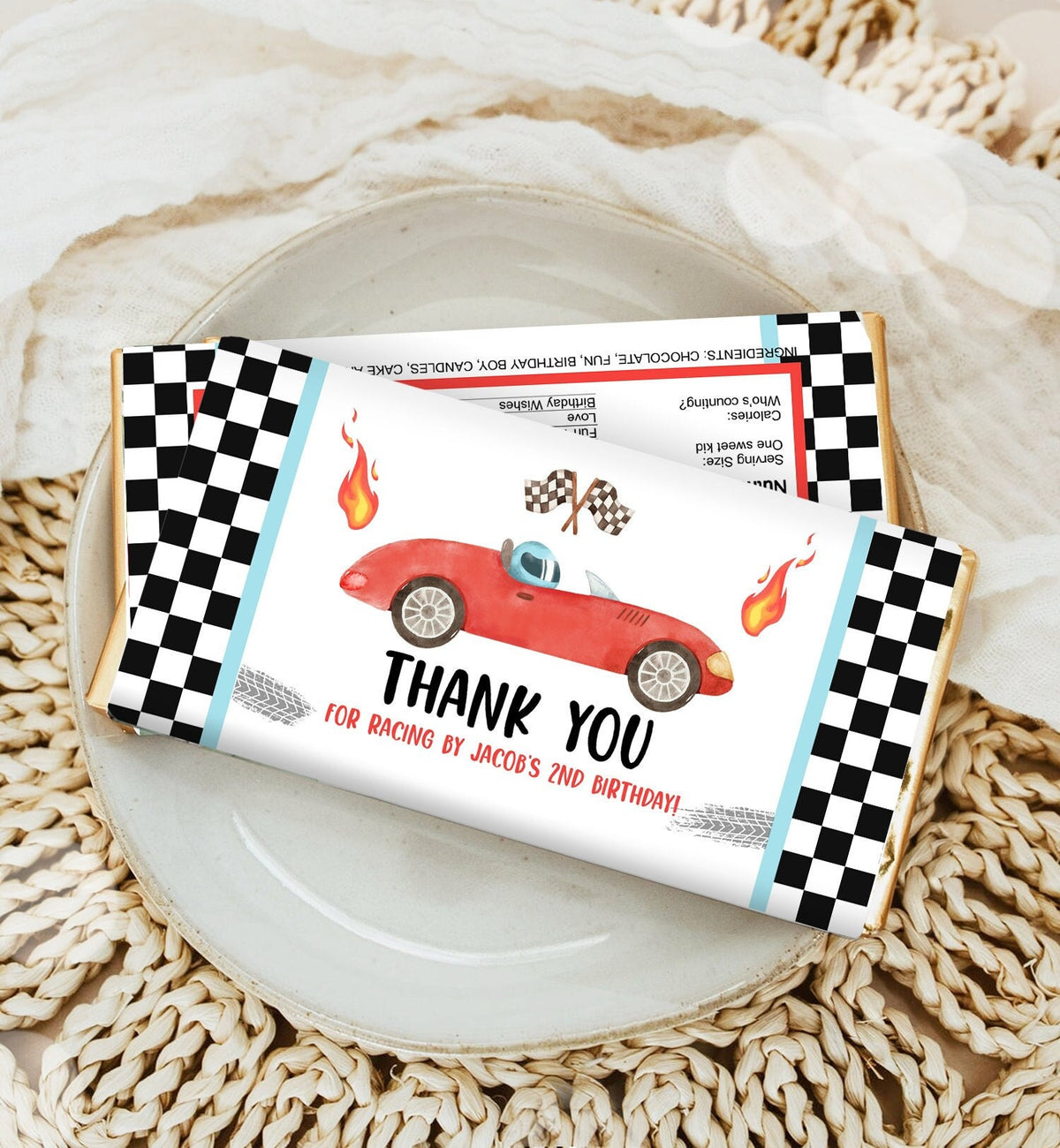 May include: A red race car with checkered flags and flames on a white chocolate bar wrapper. The wrapper has a black and white checkered border. The text on the wrapper reads &amp;#39;Thank You for racing by Jacob&amp;#39;s 2nd birthday!&amp;#39;.